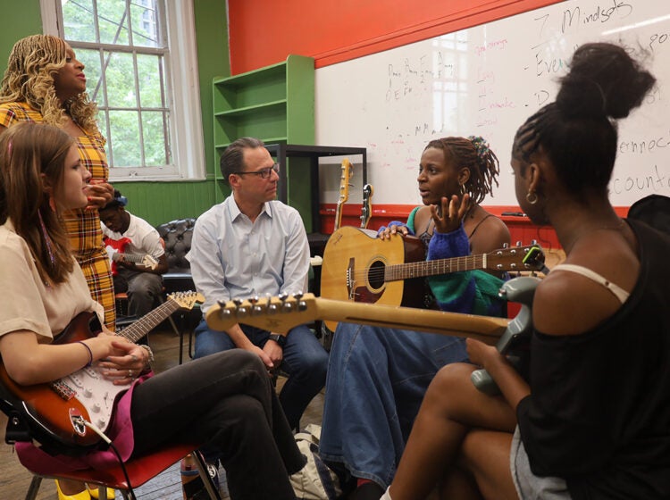 Pennsylvania Gov. Josh Shapiro listens as he sits with students holding guitars