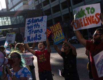 Protestors hold signs to demonstrate their support for transgender children