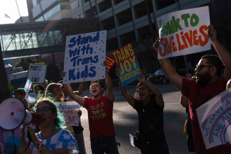 Protestors hold signs to demonstrate their support for transgender children