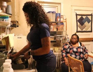 Jasmine Henderson, a home health aide, washes dishes as Altonya Sheppard looks on
