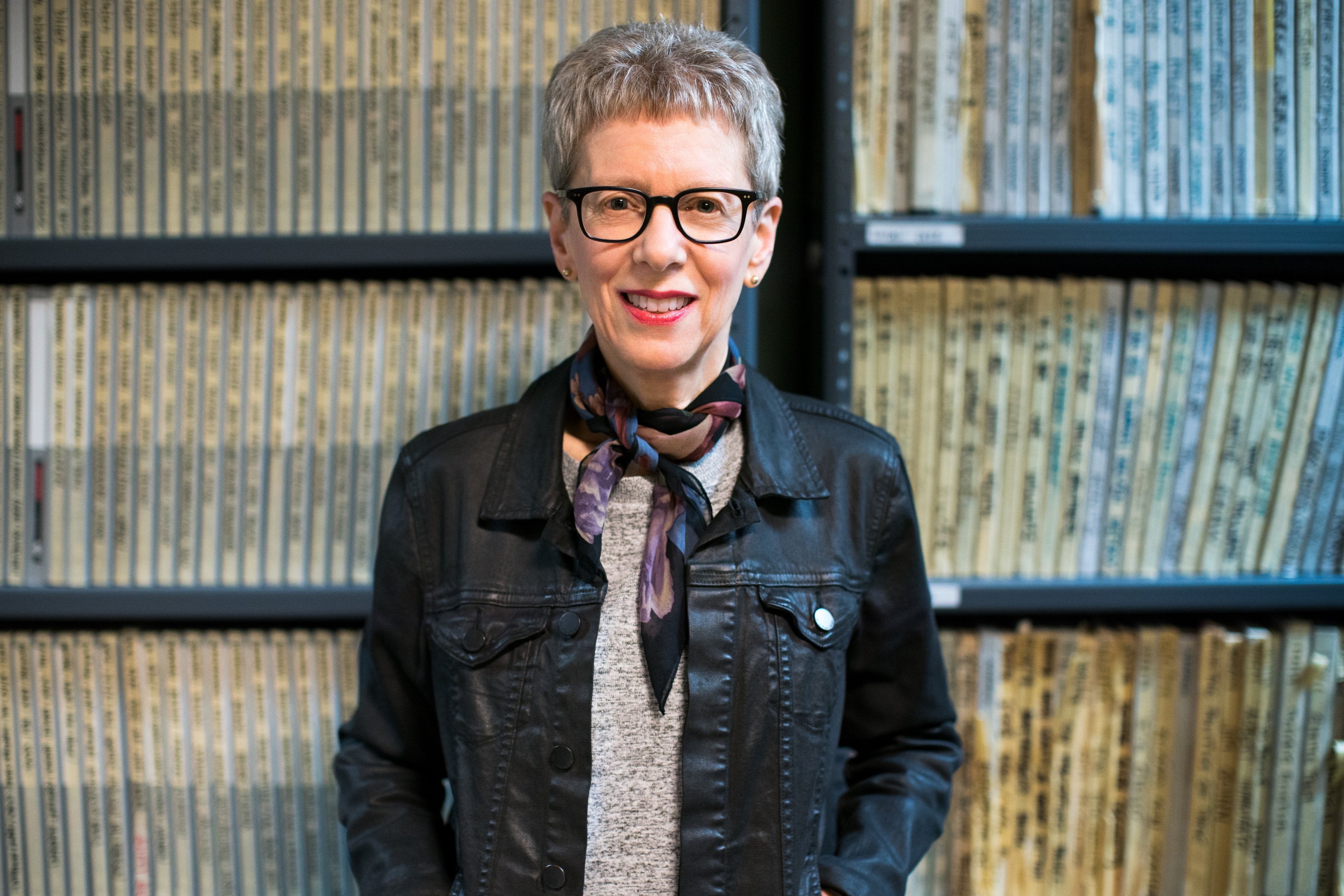 A close up portrait view of Terry Gross in front of shelves of archived folders