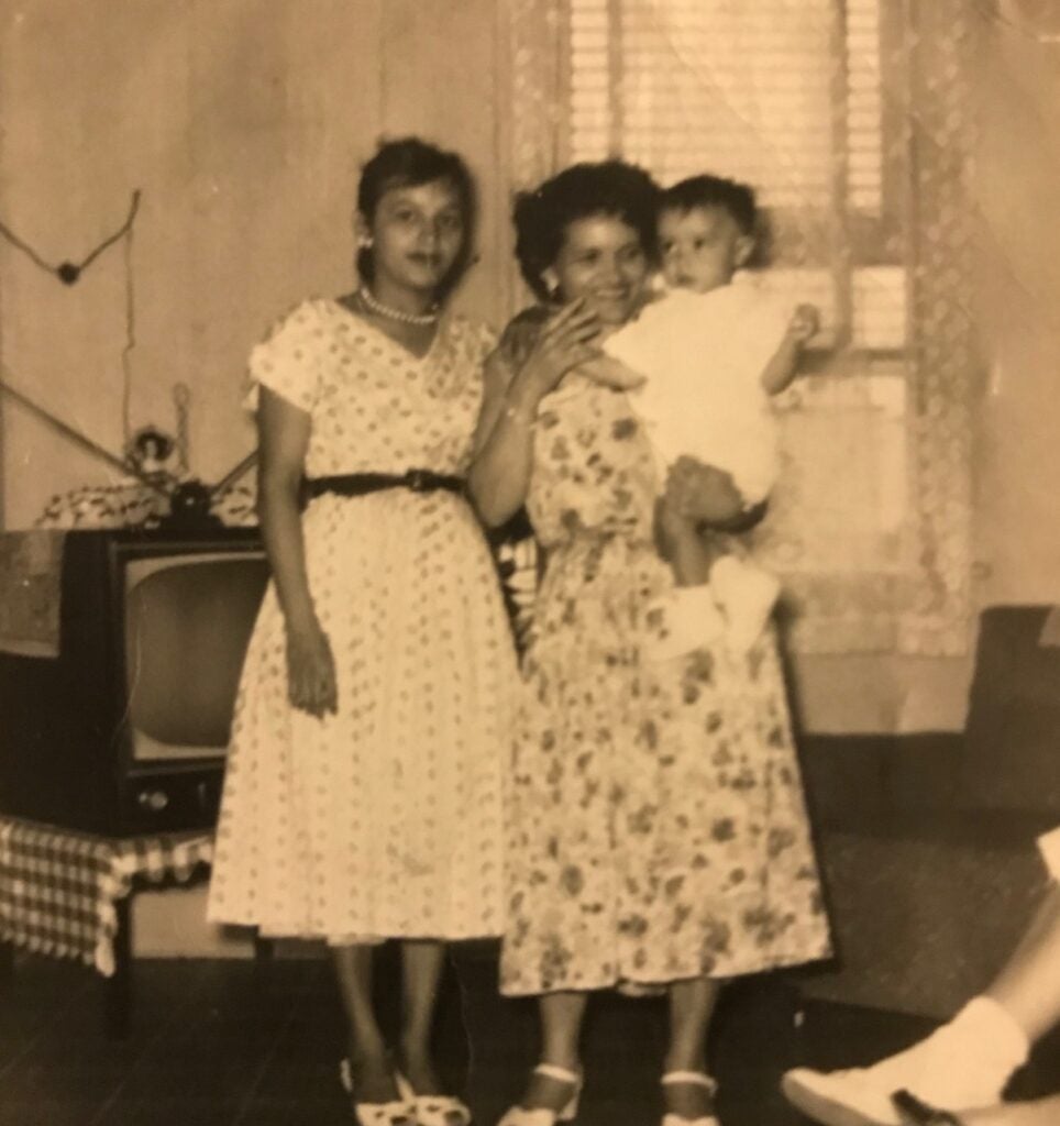 An old photo of 2 women posing with a baby in one of their arms