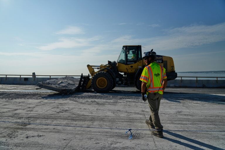 A demolition crew member walking toward a bulldozer