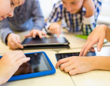 education, elementary school, learning, technology and people concept - close up of school kids with tablet pc computers having fun and playing on break in classroom