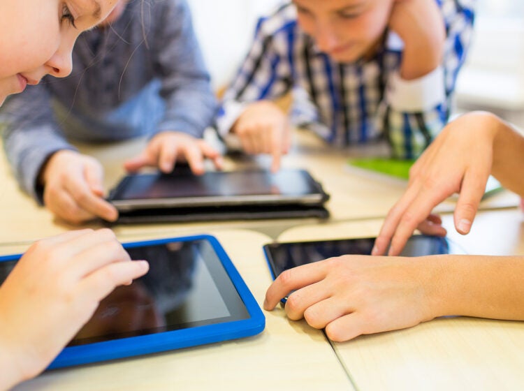 education, elementary school, learning, technology and people concept - close up of school kids with tablet pc computers having fun and playing on break in classroom