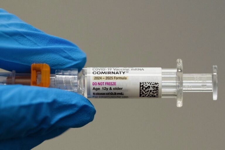 Be Well-Summer Colds Someone wearing blue gloves holding a needle with a vaccine shot