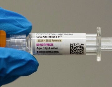 A pharmacist holds a Pfizer and BioNTech COVID-19 vaccine shot