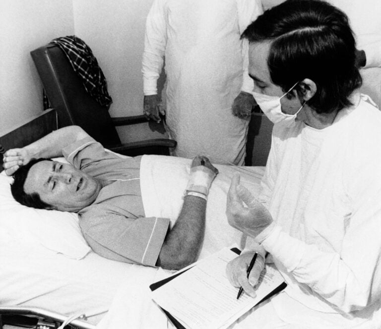 Dr. Stephen Thacker, right, of the U.S. Center for Disease Control, interviews Thomas Payne in Chambersburg Hospital in Pennsylvania, Aug. 4, 1976. Payne was one of the Legionnaires who became ill after attending a state convention in Philadelphia.  (AP Photo/Pool)