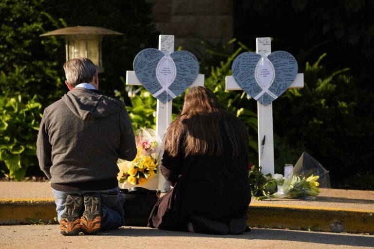 minneapolis-catholic-school-shooting-memorial-2025-08-28-ap Two people praying at a memorial for slain kids in a Minneapolis school shooting