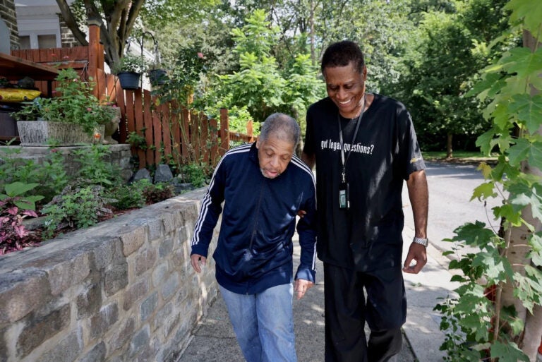 a man helps an older man walk
