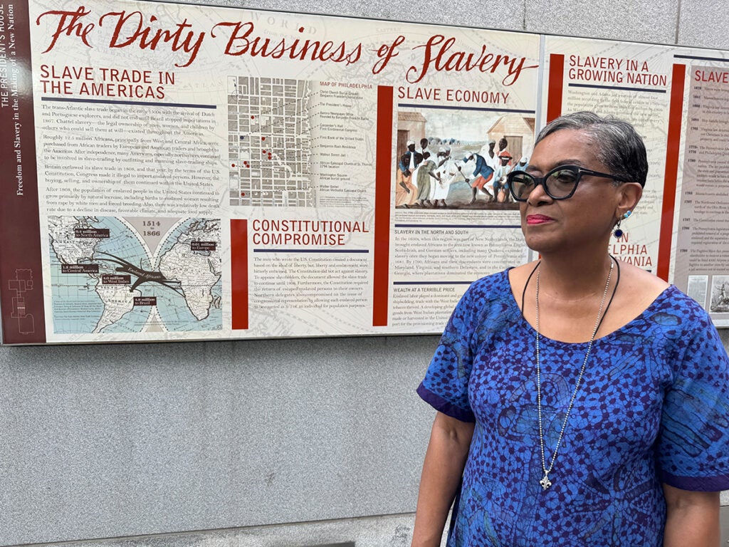 Roz McPherson stands in front of a panel exhibit about slavery