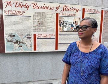 Roz McPherson stands in front of a panel exhibit about slavery