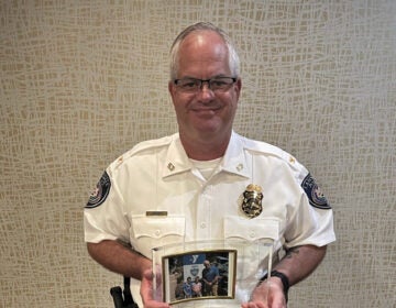 Michael Train posing with a photo of himself with some children