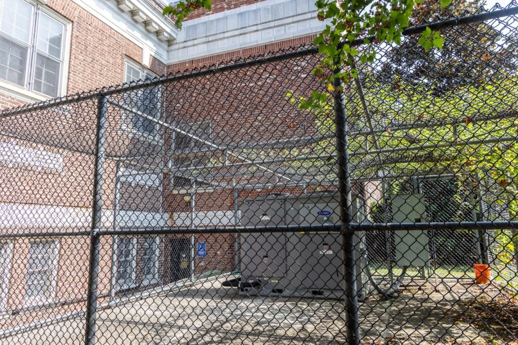 An HVAC system outside in a fenced area.