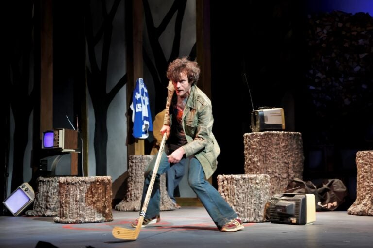 A scene from the play features an actor practicing with a hockey stick