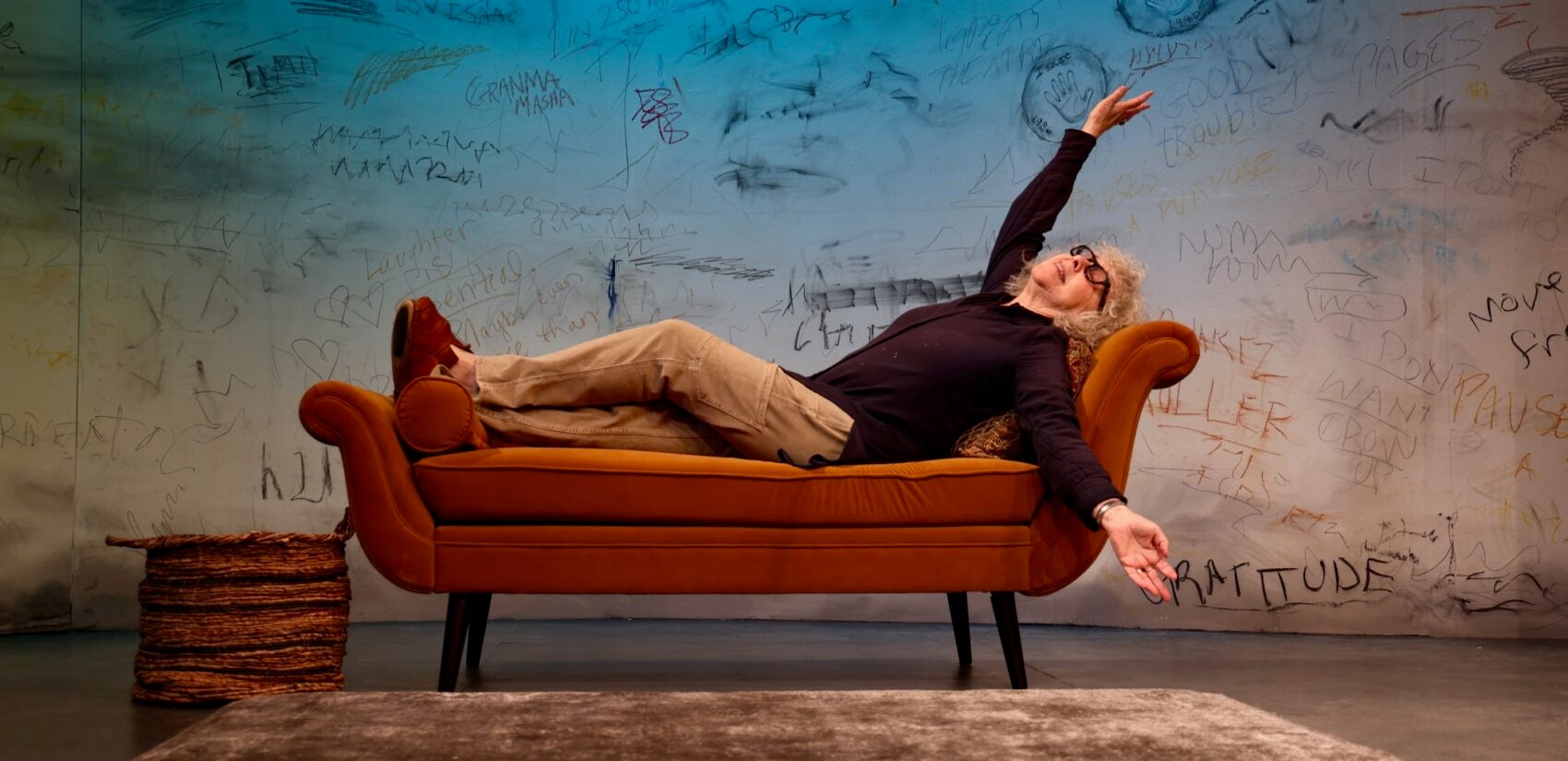 Kathryn Grody horizontal on a couch on stage