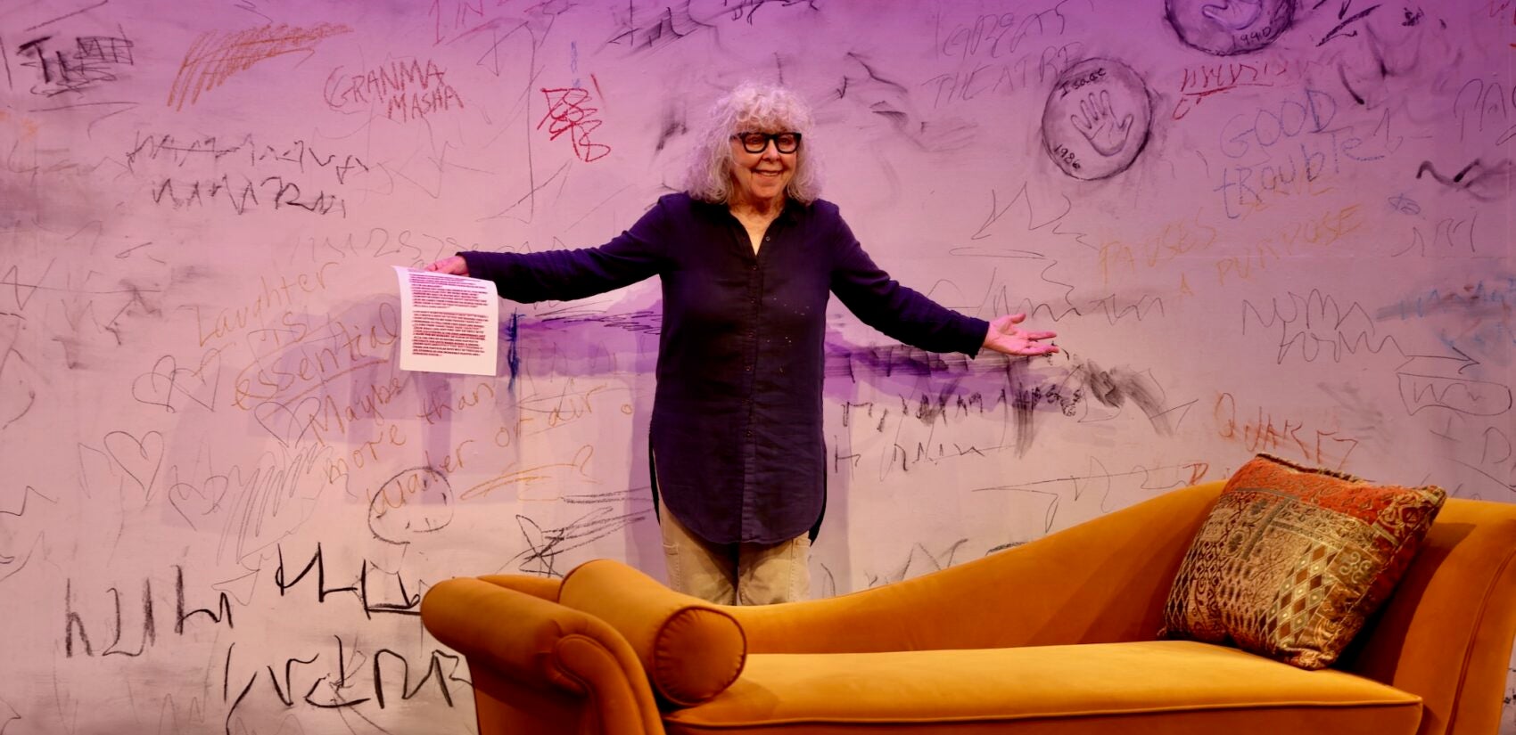 Kathryn Grody holds a page of the script for her one-woman show on stage