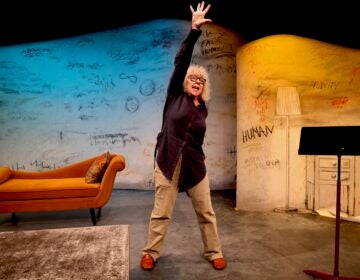 Kathryn Grody on stage reaching an arm up