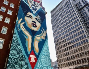 ''Uplift Justice'' by Shepard Fairey, a mural featuring a woman's face and her hands held up below her chin, is painted on the side of a Center City office building on Arch Street