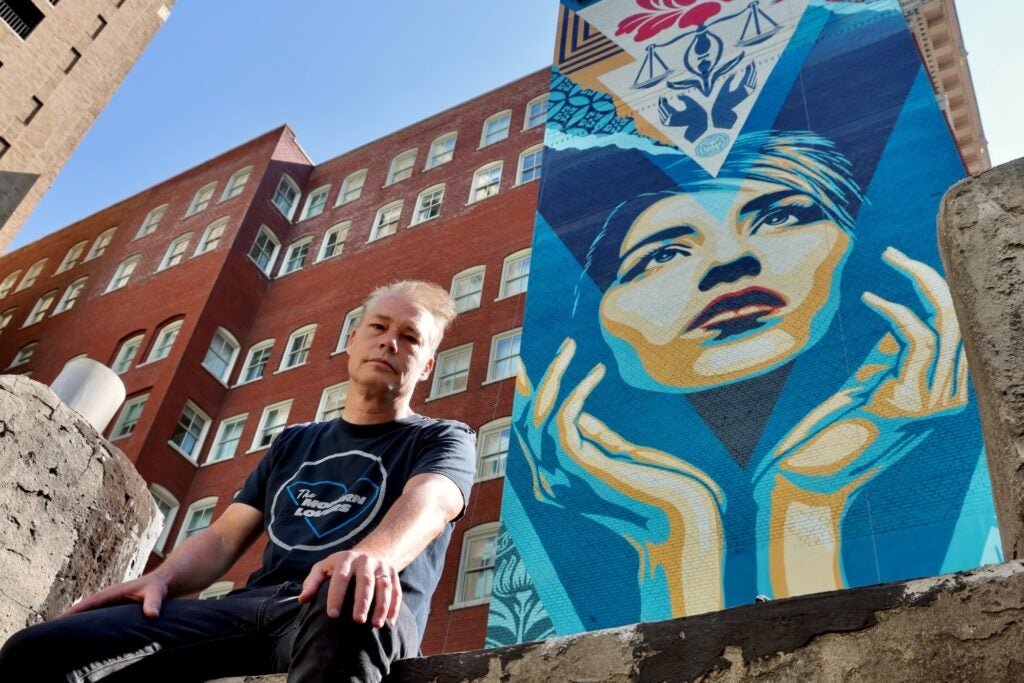 Shepard Fairey sits on a rooftop beside his new mural, ''Uplife Justice.''