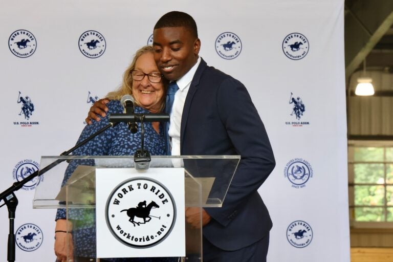 Lezlie Hiner and Kareem Rosse hug while standing at a podium
