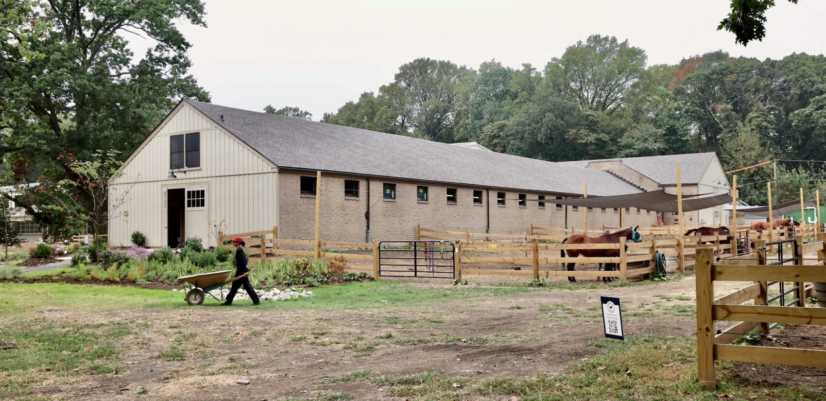 2025 09 24-e lee-philadelphia fairmount park chamounix stables-new arena stables A person pushes a wheelbarrow outside at the compout
