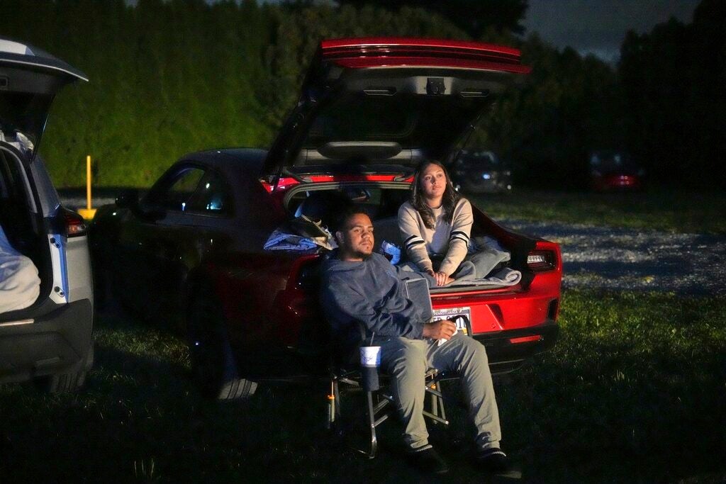 A couple watch a movie at a drive-in theater in the back of a car