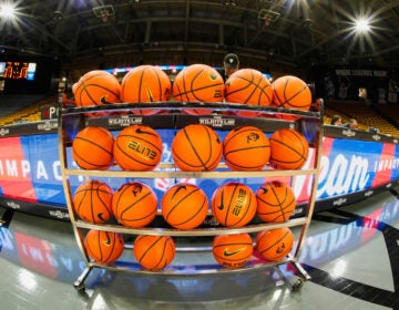 Basketballs sit on a rack on a court