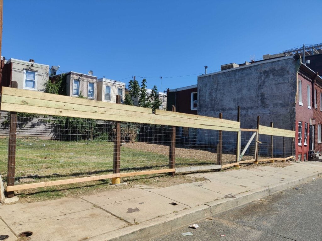 A new fence goes around an abandoned lot.