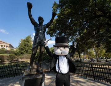 Mr. Monopoly posing with the Rocky statue