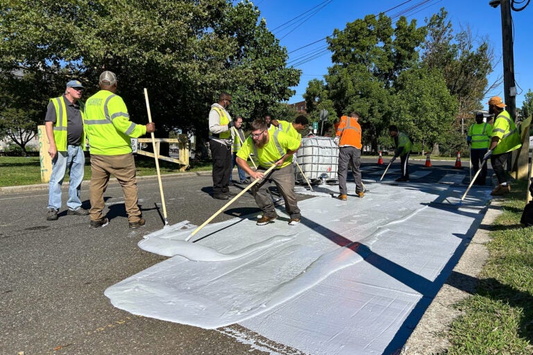 Workers spread the white coating along the road