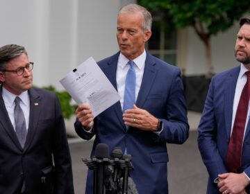 John Thune speaking, with Mike Johnson and JD Vance standing on either side of him during a press conference