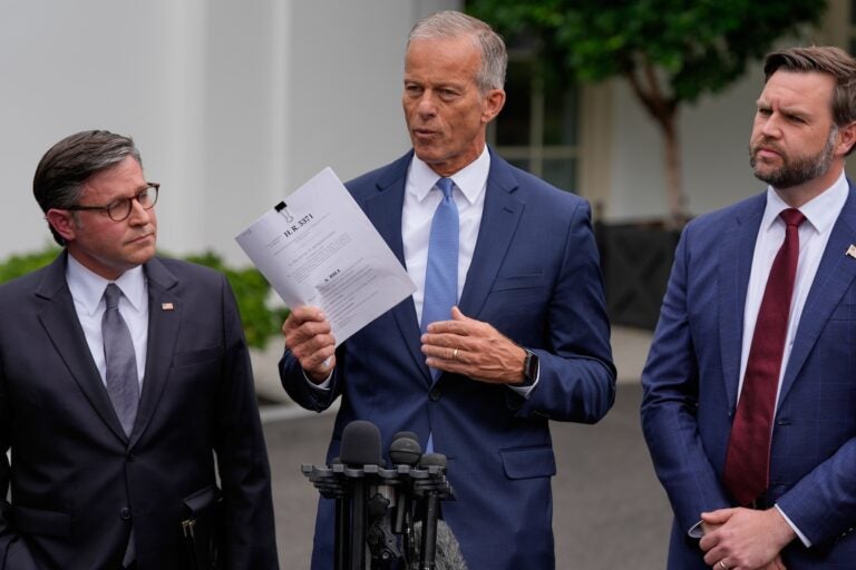 John Thune speaking, with Mike Johnson and JD Vance standing on either side of him during a press conference