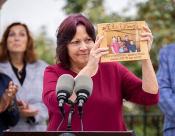 A woman holds up a framed photo of her family