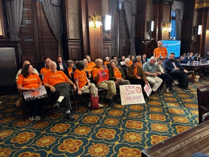 People sit with signs advocating for gun control legislation at the Pennsylvania Legislature