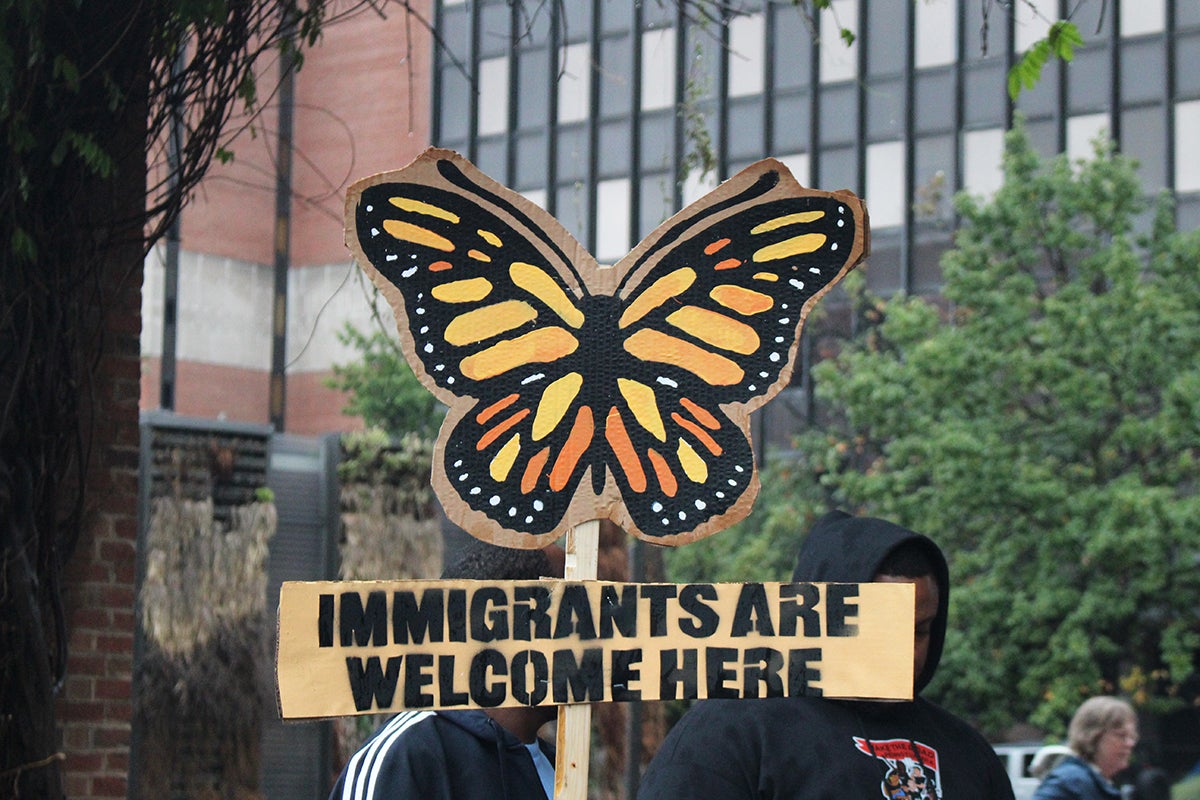 a sign at an immigrant rights rally in Philadelphia shows a butterfly and reads IMMIGRANTS ARE WELCOME HERE