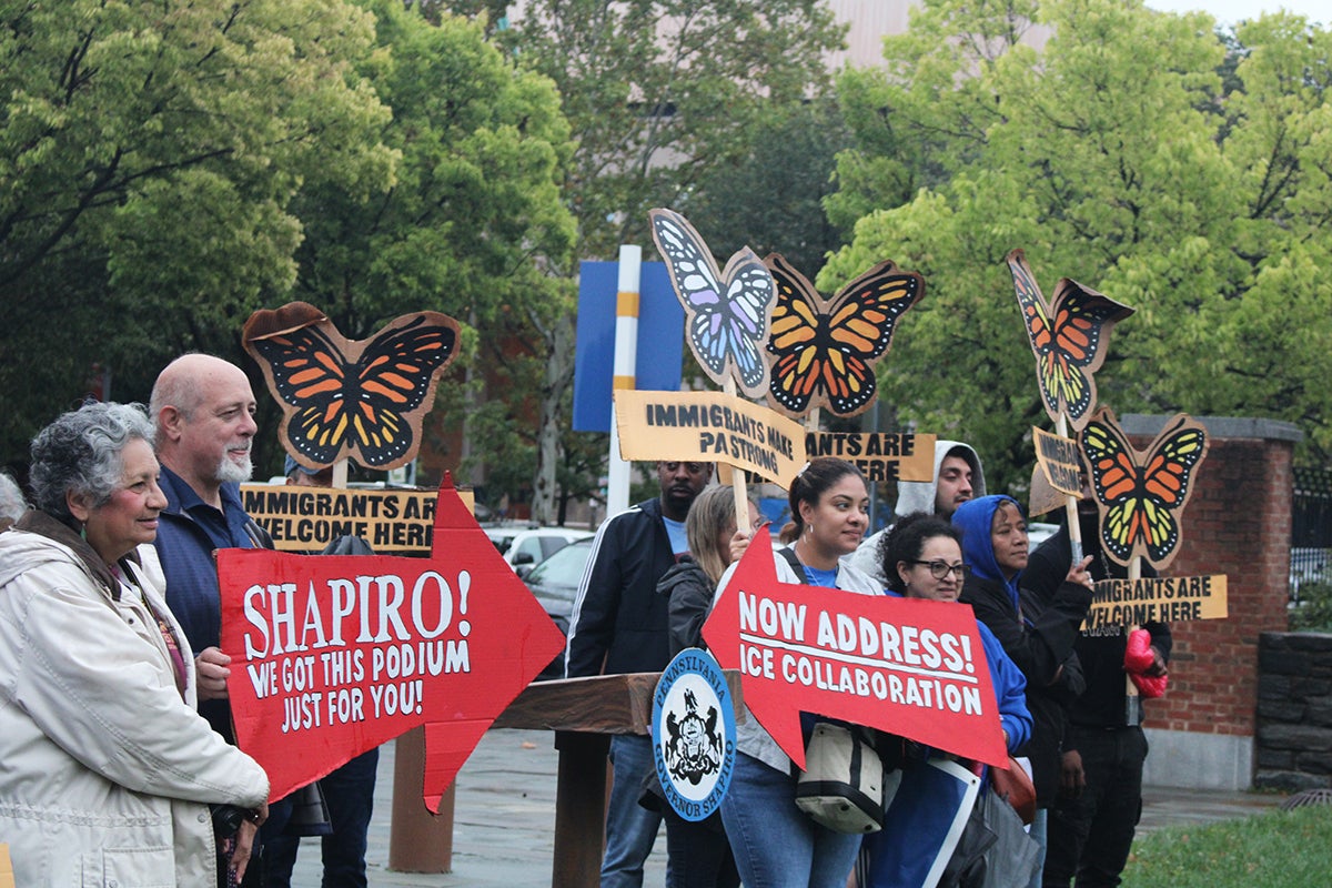 Immigrant advocates hold signs at a rally in Philadelphia