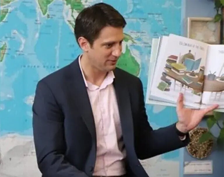 Justin Lee Smith holding up a book in a classroom