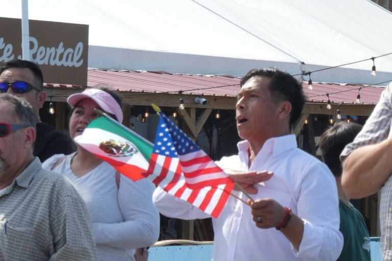 a man holds American and Mexican flags