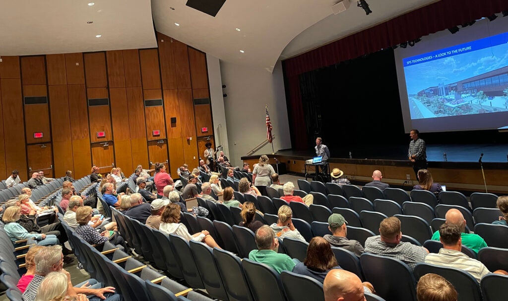 Representatives from SPS Technologies speak to members of the Abington community inside an auditorium.