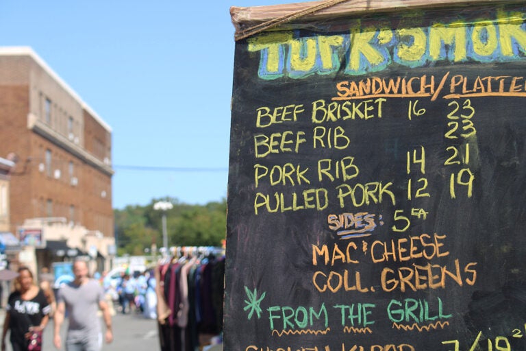 A blackboard sign lists various food items at the Upper Darby International Festival