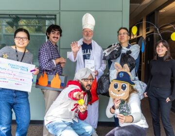 Billy Penn’s 2025 Halloween Costumes (Kimberly Paynter/WHYY) The Billy Penn staff posing for a photo outside of Terry Gross' office wearing their bespoke unique halloween costumes, led by Nick Kariuki as the Phillies Karen