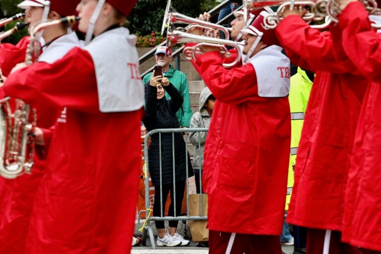 A spectator photographs the Temple University marching band