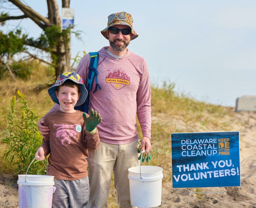 A man with a child posing for a photo at the beach cleanup