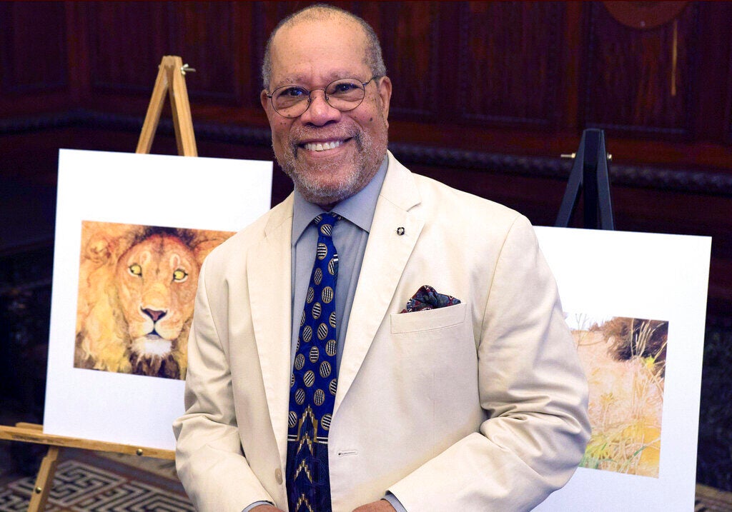 Children's book illustrator Jerry Pinkney poses in front of two of his illustrations