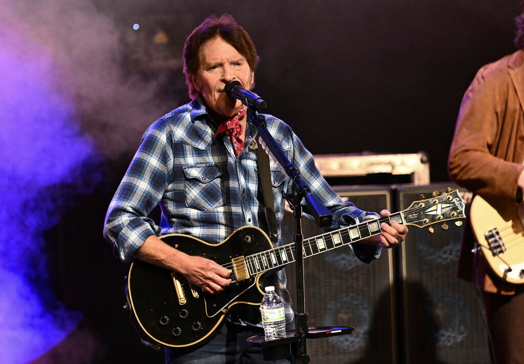 Musician John Fogerty plays a guitar on stage