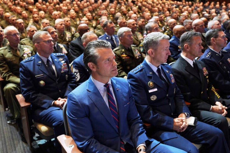 Defense Secretary Pete Hegseth, center, sitting with Chairman of the Joint Chiefs of Staff Air Force Gen. Dan Caine, third from right, and U.S. military senior leadership as they listen to President Donald Trump speaks at Marine Corps Base Quantico, Tuesday, Sept. 30, 2025 in Quantico, Va. (AP Photo/Evan Vucci)