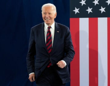 Former President Joe Biden stands in front of an American flag