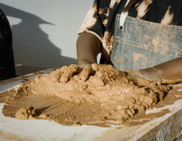 A person working with red clay on a table