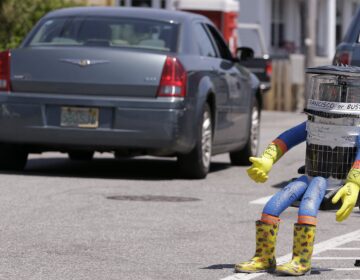 a robot sitting on a chair on the side of the road with it's thumb up for hitch hiking